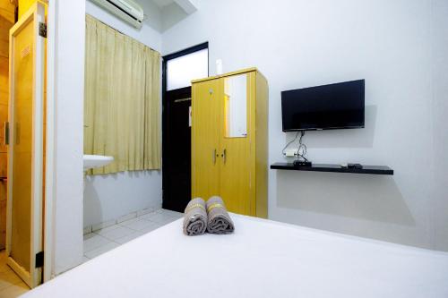 a pair of shoes in a room with a television at Marcello Residence Siwalankerto near Petra University Surabaya Mitra RedDoorz in Surabaya