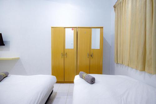 a room with two beds and a wooden locker at Marcello Residence Siwalankerto near Petra University Surabaya Mitra RedDoorz in Surabaya