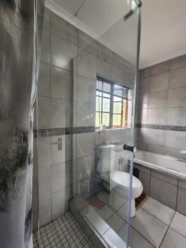 a bathroom with a shower with a toilet and a tub at Bela-Bela Pendleberry Grove Unit 3 in Bela-Bela