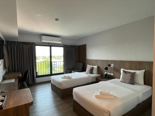 a hotel room with two beds and a window at Nakara Hotel, Ubon Ratchathani in Ban Na Kham