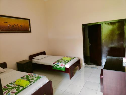 a small room with two beds and a window at Berlian Inn Kuta Beach in Kuta