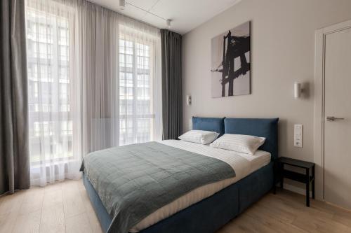 a bedroom with a blue bed and two windows at FORUM apart in Lviv