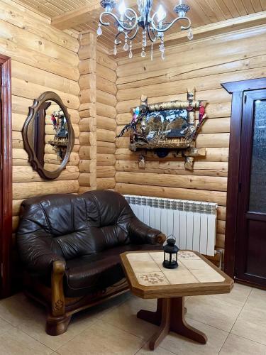 a leather couch in a room with a mirror and a table at Садиба Карпат in Verkhovyna