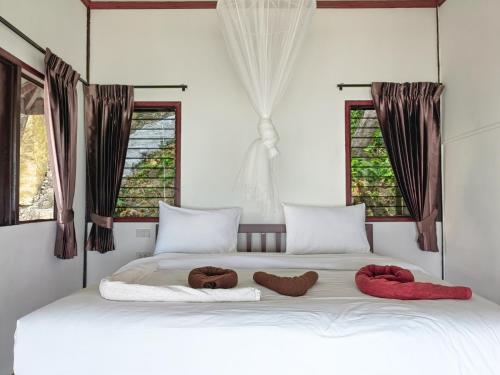 Phi Phi Private Beach Resort في جزيرة في في: سرير أبيض عليه منشفتين مع نوافذ