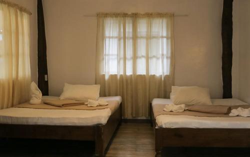 two twin beds in a room with a window at Southdrive Beach Resort in Bulalakao