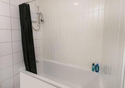 y baño con ducha con cortina negra. en 3 Bedroom Apartment - Big special offer for long stays, en Lincolnshire