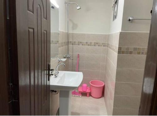 a bathroom with a sink and a pink bucket at Marine Tower in Rawalpindi
