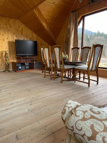 a living room with a table and chairs and a television at Садиба Карпат in Verkhovyna