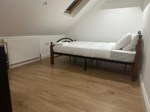 a bed in a room with a wooden floor at Tran UK Homestay in London