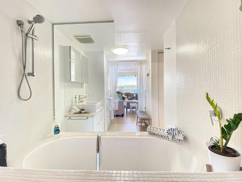 a white bathroom with a tub and a sink at 1 Bright Point Apartment 3104 in Nelly Bay