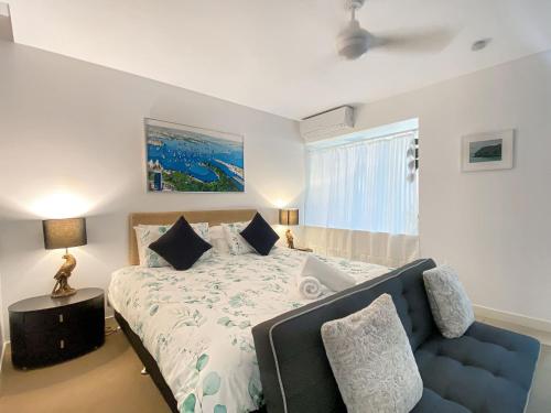 a bedroom with a bed and a blue couch at 1 Bright Point Apartment 3104 in Nelly Bay