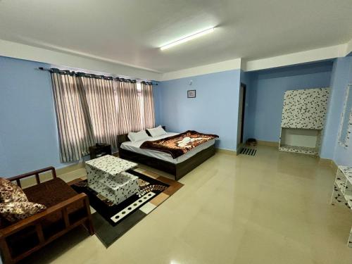 Hotel Vivid Tawang في تاوانج: غرفة نوم بجدران زرقاء وسرير واريكة
