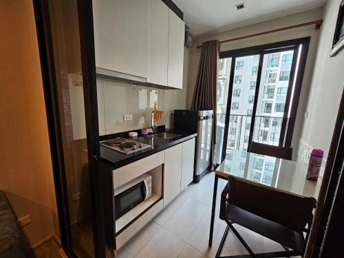 a kitchen with a stove and a table and a window at The Base Central Pattaya by Leya in Pattaya