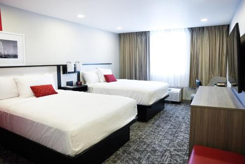 a hotel room with two beds and a desk at Ramada by Wyndham DFW Airport in Irving