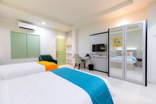 a hotel room with two beds and a desk at Sans Hotel 88 Andalan Surabaya by RedDoorz in Surabaya