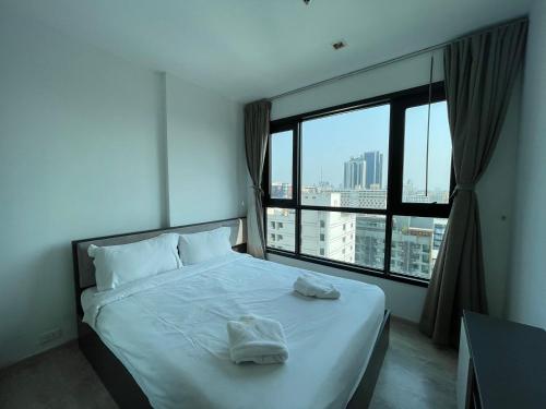 a bedroom with a bed and a large window at The Base Central Pattaya by Leya in Pattaya Central