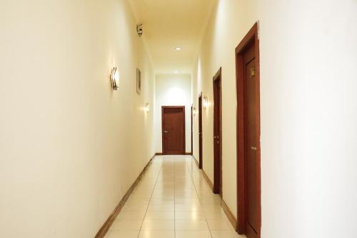 a hallway with white walls and a brown door at Urbanview Hotel Ratu Elok Syariah Banjarbaru by RedDoorz in Martapura