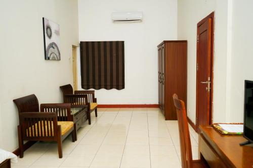 a waiting room with chairs and a table and a television at Urbanview Hotel Ratu Elok Syariah Banjarbaru by RedDoorz in Martapura