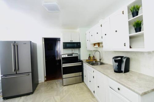 een keuken met witte kasten en een roestvrijstalen koelkast bij Spacious perfect 2BR in prime location in Kingston