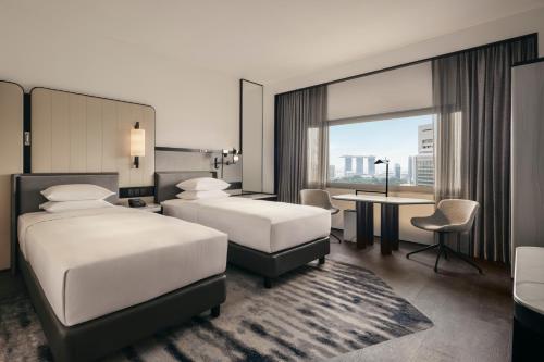 a hotel room with two beds and a desk at Hilton Singapore Orchard in Singapore