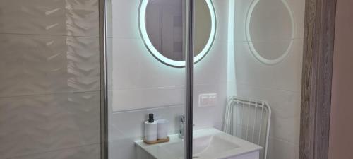 y baño con ducha, lavabo y espejo. en Kolorowe Cieplice - Apartamenty z widokiem na Karkonosze en Jelenia Góra