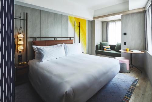 a bedroom with a large white bed and a living room at voco Osaka Central by IHG in Osaka