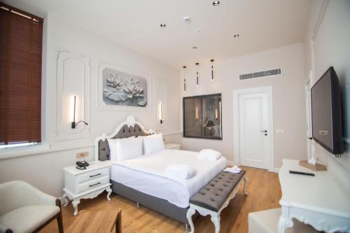 ein weißes Schlafzimmer mit einem Bett und einem TV in der Unterkunft S CLASS HOTEL CONVENTION CENTER in Güllüce