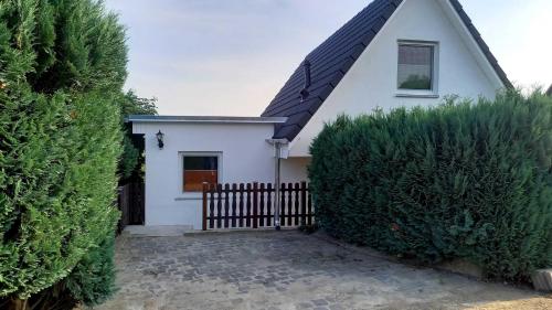 a white house with a fence and some bushes at Ferienhaus in Salem am Kummerower See in Salem