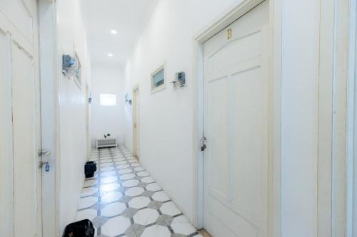 a hallway with white doors and a tile floor at Urbanview Blessing Residence Surabaya by RedDoorz in Surabaya