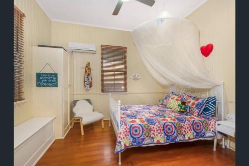 a bedroom with a bed with a canopy and a chair at Beautiful house with city views in Brisbane