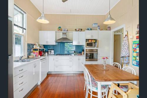 a kitchen with white cabinets and a wooden table at Beautiful house with city views in Brisbane