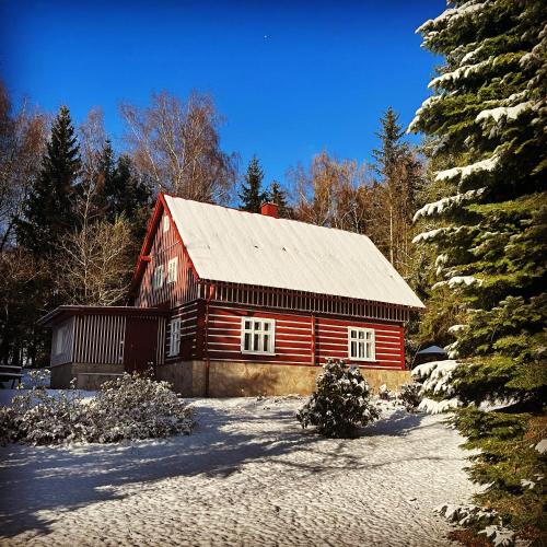 a red barn with a silver roof in the snow at Chalupa Janovice in Rudník