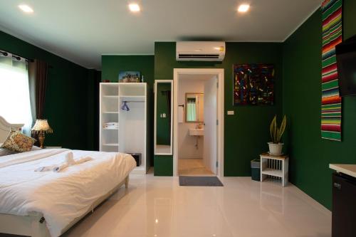 a bedroom with green walls and a white bed at Hacienda Resort - Mae Phim in Mae Pim