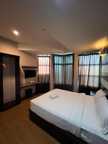 a bedroom with a large white bed and windows at Hotel Economy Kapar in Kapar