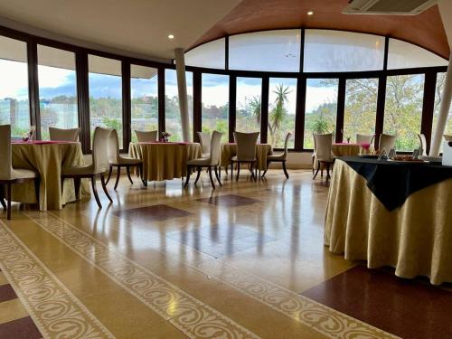 una sala da pranzo con tavoli, sedie e finestre di Ares Hotel a San Giovanni la Punta