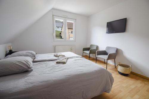 1 dormitorio con 1 cama, 2 sillas y TV en Vacance au Bonhomme, en Le Bonhomme