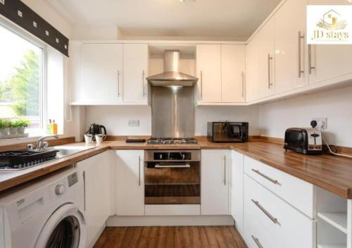 La cuisine est équipée de placards blancs et d'un four avec plaques de cuisson. dans l'établissement 3 Bedroom Apartment, family & business - Big special offer for long stays, à Lincolnshire