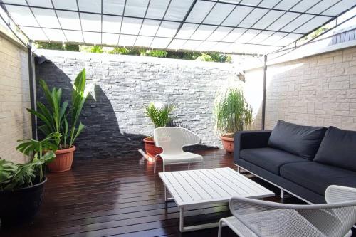 Un patio con un sofá y una mesa y plantas. en HEITEA LODGE - 6 min airport, Wifi, AC & Parking, en Papeete