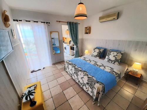Cet appartement comprend une chambre avec un lit bleu et blanc et une cuisine. dans l'établissement Les Chambres d'Hôte du Pavé, à Saint-Paul