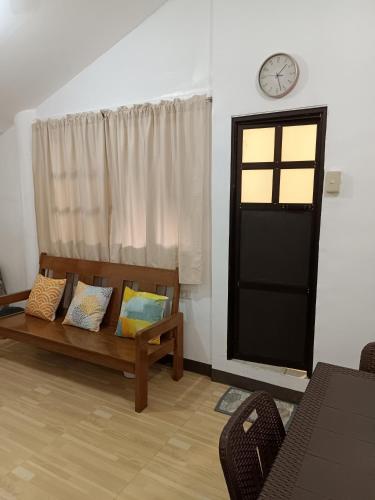 a living room with a couch and a clock on the wall at Elisha's Guest House in Coron