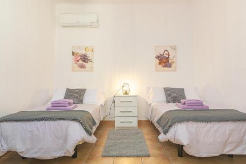 two twin beds in a room with a night stand at Cas Decu in Fornalutx