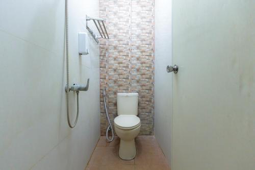 een badkamer met een toilet en een bakstenen muur bij RedDoorz at Osuko Residence Sukomanunggal Jaya in Surabaya