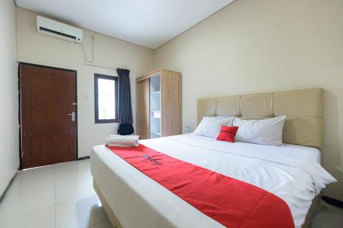 una camera da letto con un grande letto con una coperta rossa di RedDoorz at Osuko Residence Sukomanunggal Jaya a Surabaya