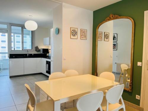 a dining room with a table and chairs and a mirror at Central, confort, 2 chambres, parking - Lyon 6e in Lyon