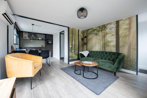 uma sala de estar com um sofá verde e uma mesa em 20, Nestled in the woods, Big Chalet and Garden! em Oisterwijk