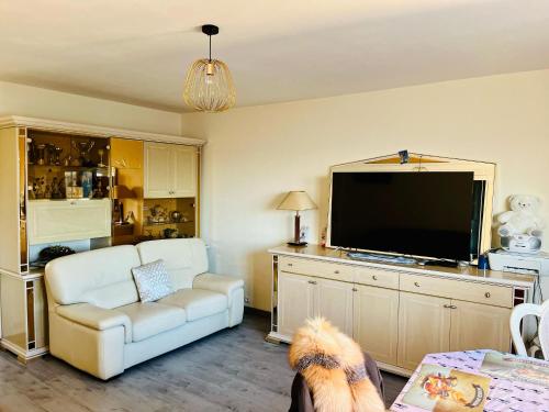 een woonkamer met een witte bank en een flatscreen-tv bij Booking in Clichy