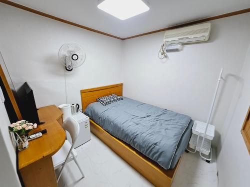 ein kleines Schlafzimmer mit einem Bett, einem Schreibtisch und einem Computer in der Unterkunft K Highstel in Seoul