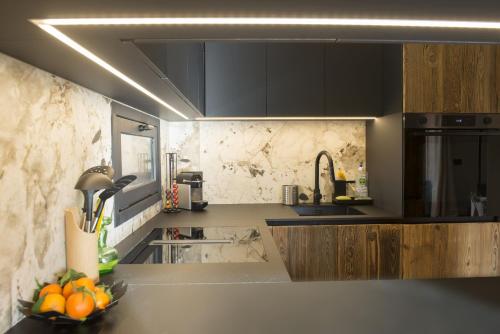 une cuisine avec des armoires noires et un bol d'oranges sur un comptoir dans l'établissement SmartStay Cocon Alpin - Meribel, à Les Allues