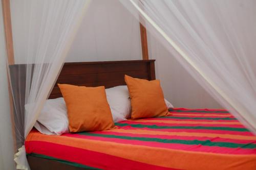 un letto con cuscini arancioni e bianchi di Yino Villa a Midigama East