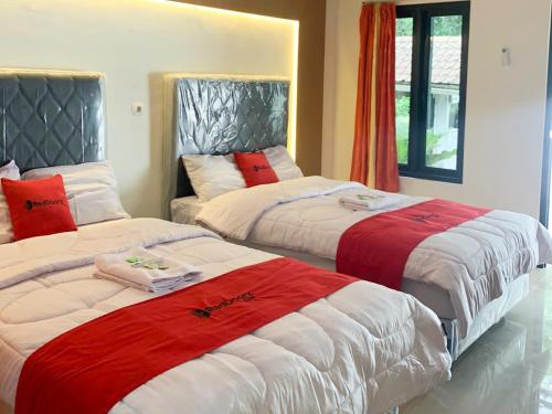 a bedroom with two beds with red and white sheets at RedDoorz near Museum Gunung Merapi in Yogyakarta